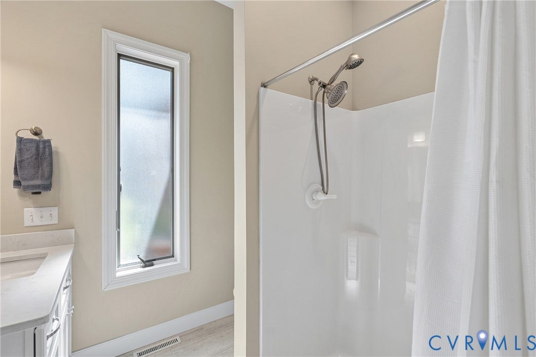 447 Tranquility Road, Reedville, VA 22539 Bathroom featuring a shower with a two-head fixture, a vanity with an undermount sink, and a vertical frosted window