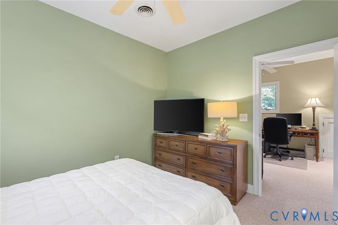 447 Tranquility Road, Reedville, VA 22539 Ceiling fan, light green wall paint, wood-finish dresser, neutral carpet, open doorway