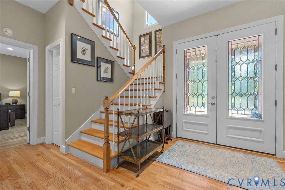 447 Tranquility Road, Reedville, VA 22539 Wood-finish flooring, a wood staircase with white risers, and decorative glass double entry doors