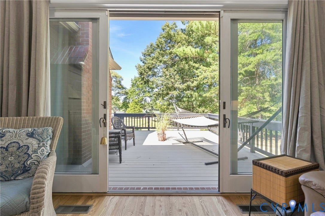 447 Tranquility Road, Reedville, VA 22539 Wood-finish flooring leading to a glass sliding door, opening to an expansive outdoor deck with a black railing system