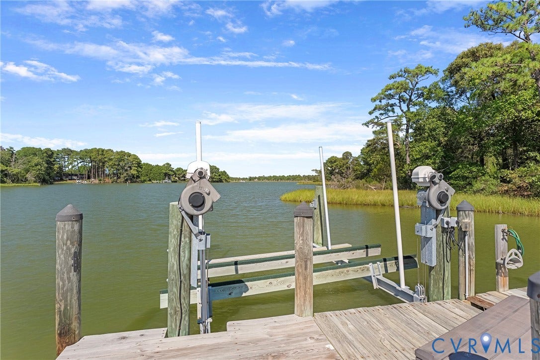 447 Tranquility Road, Reedville, VA 22539 Private dock with a boat lift, featuring wooden decking and pilings, set against a natural shoreline