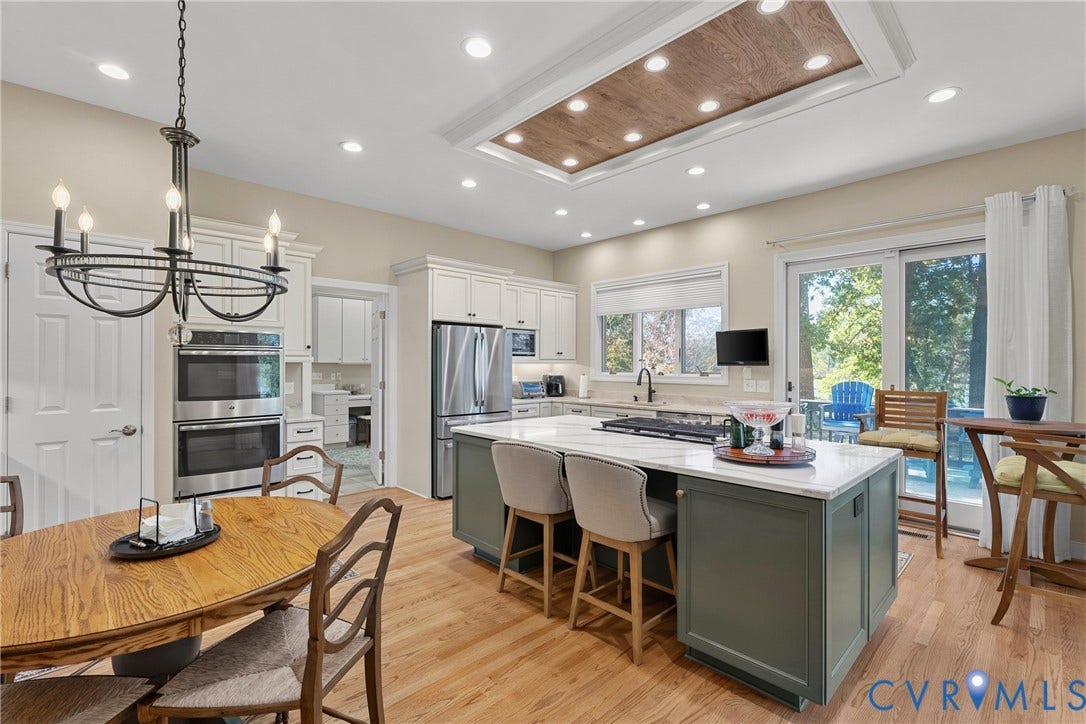 447 Tranquility Road, Reedville, VA 22539 Kitchen featuring light wood-finish flooring, white cabinetry, stainless steel appliances, a center island with countertop seating, and a tray ceiling with recessed lighting