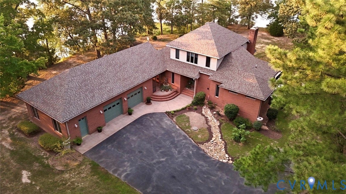 447 Tranquility Road, Reedville, VA 22539 Brick exterior with a multi-level roofline, attached garage, paved drive, and mature trees