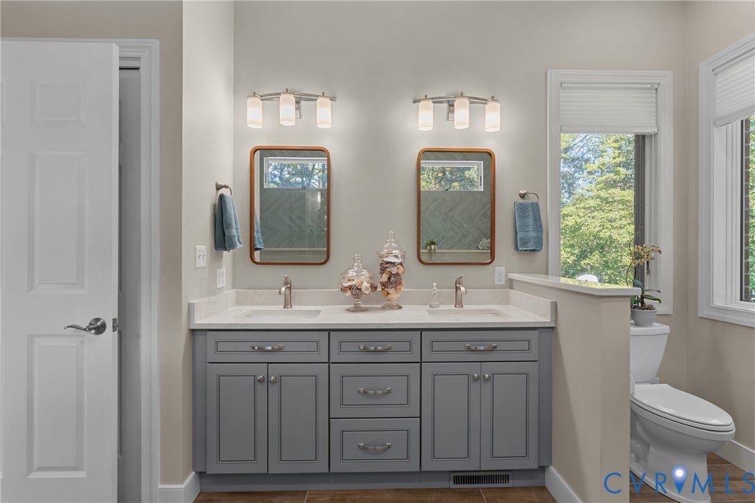 447 Tranquility Road, Reedville, VA 22539 Double vanity with gray cabinetry, white countertops, and dual wall-mounted light fixtures