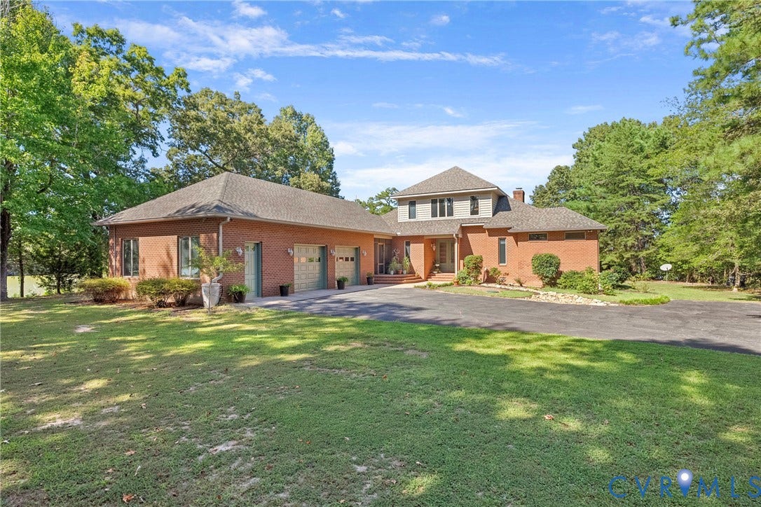 447 Tranquility Road, Reedville, VA 22539 Brick exterior with a multi-level design, attached three-car garage, and a paved driveway