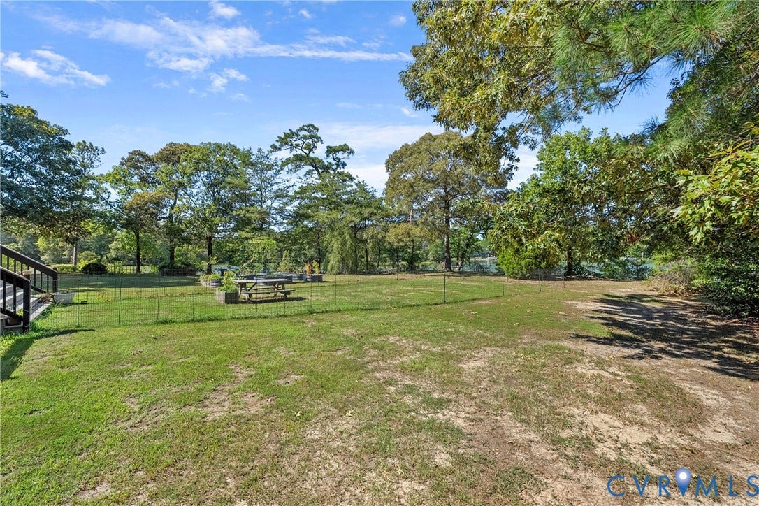 447 Tranquility Road, Reedville, VA 22539 Expansive grassy property with mature trees, raised garden beds, and a wood-finish staircase