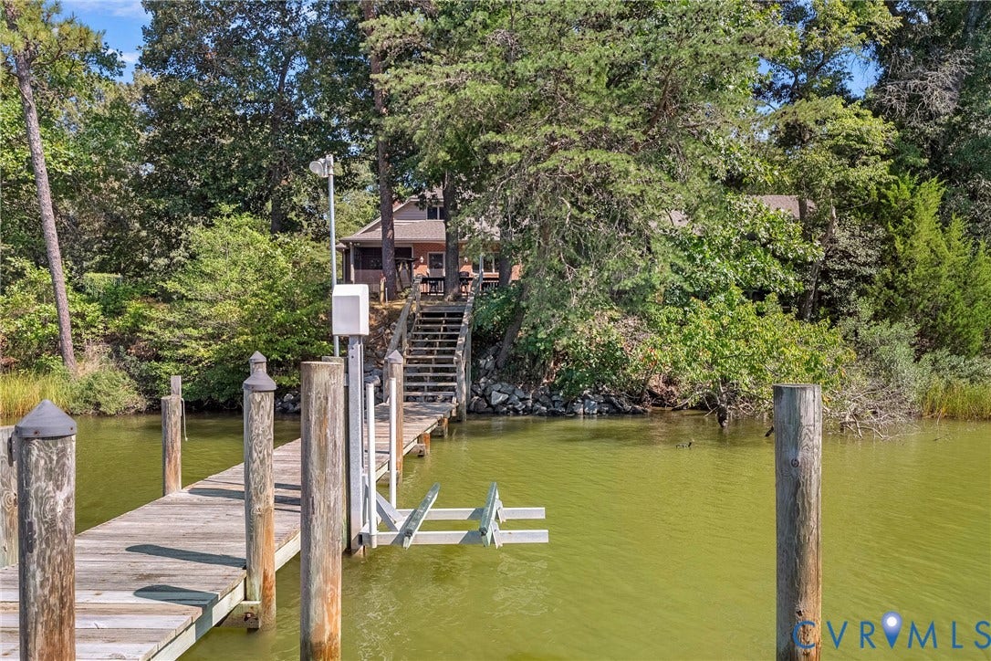 447 Tranquility Road, Reedville, VA 22539 Private wooden dock featuring a boat lift, leading to a waterside property with mature trees and a visible residential structure