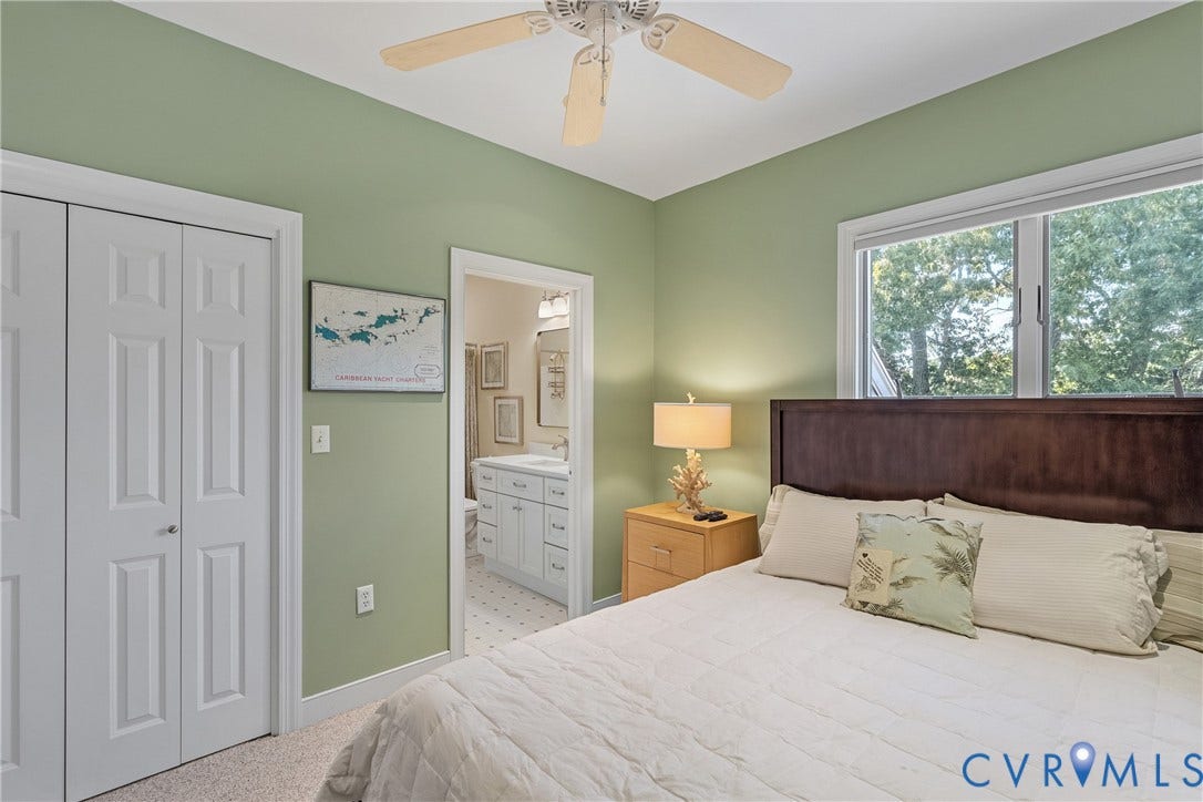447 Tranquility Road, Reedville, VA 22539 Light green walls with white trim, a ceiling fan, a window, and an adjacent bathroom with a white vanity