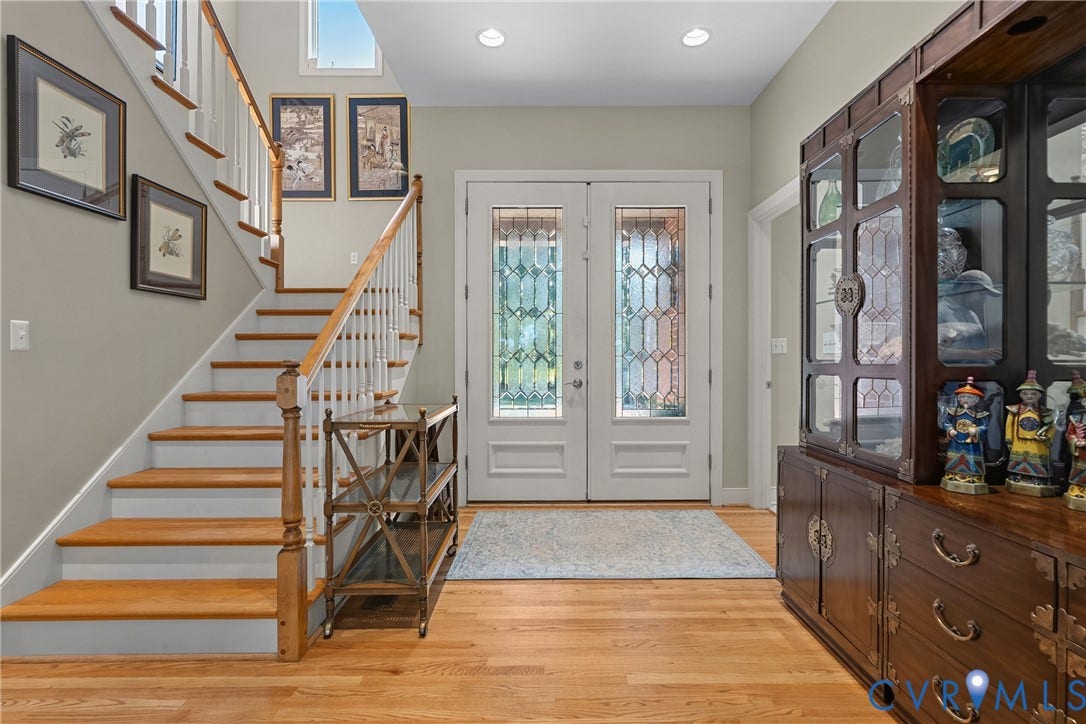 447 Tranquility Road, Reedville, VA 22539 Hardwood flooring, painted white staircase with wood handrail, double entry doors with decorative glass, recessed lighting, and upper transom windows