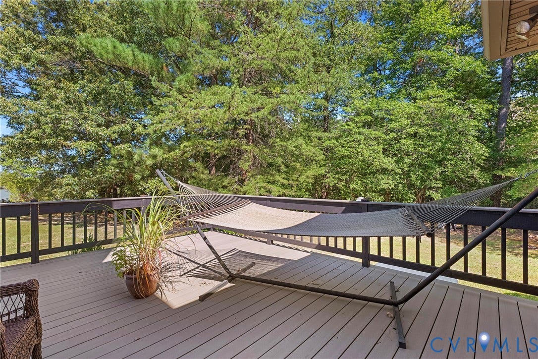 447 Tranquility Road, Reedville, VA 22539 Expansive outdoor deck featuring composite decking, dark wood railing, and surrounding mature trees