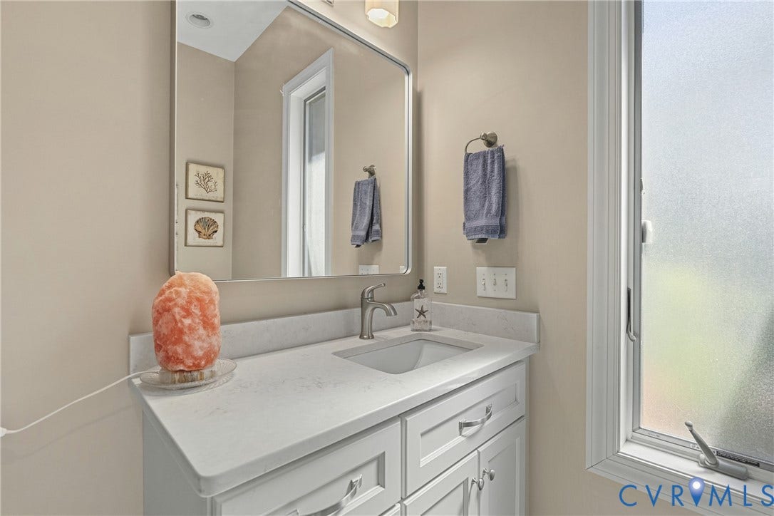 447 Tranquility Road, Reedville, VA 22539 White vanity with recessed panel cabinet doors, brushed nickel hardware, integrated sink, and light-toned countertop