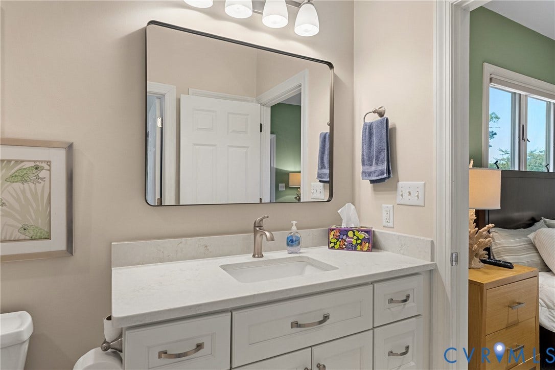 447 Tranquility Road, Reedville, VA 22539 Vanity with integrated sink, brushed nickel faucet, and a rectangular mirror with a black frame