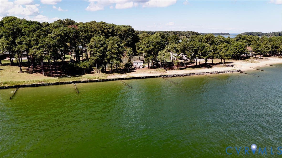 447 Tranquility Road, Reedville, VA 22539 Waterfront property featuring a sandy beach, mature tree canopy, and shoreline protection