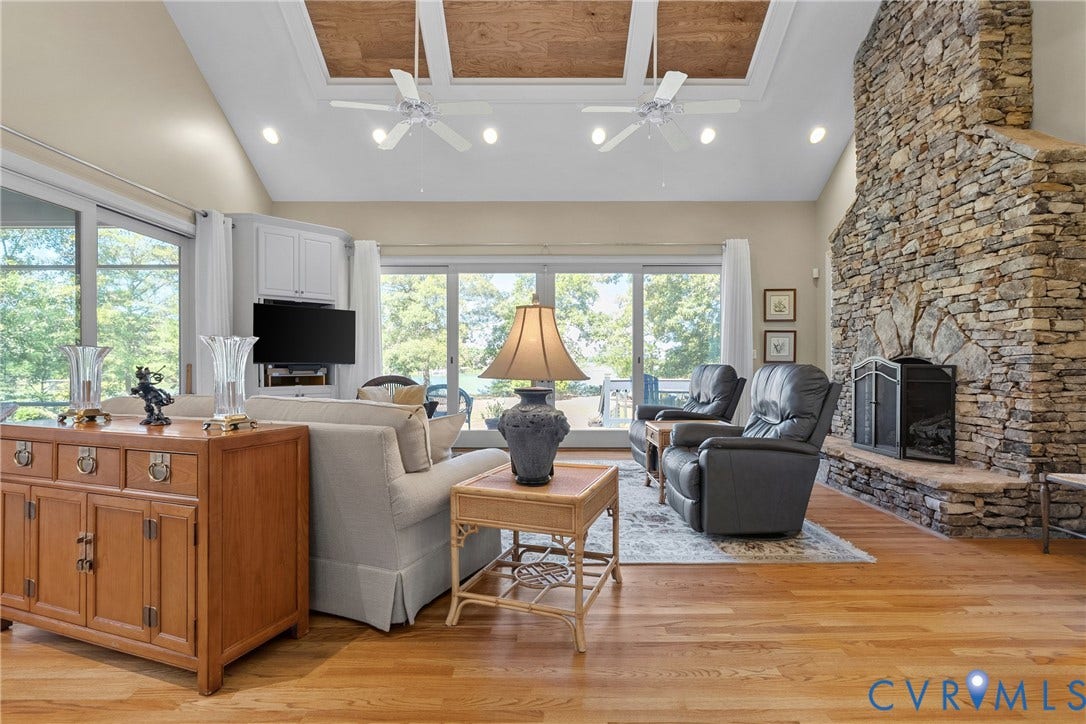 447 Tranquility Road, Reedville, VA 22539 Vaulted ceiling with wood-paneled inserts, recessed lighting, stone fireplace, wood-finish flooring, and expansive glass sliding doors
