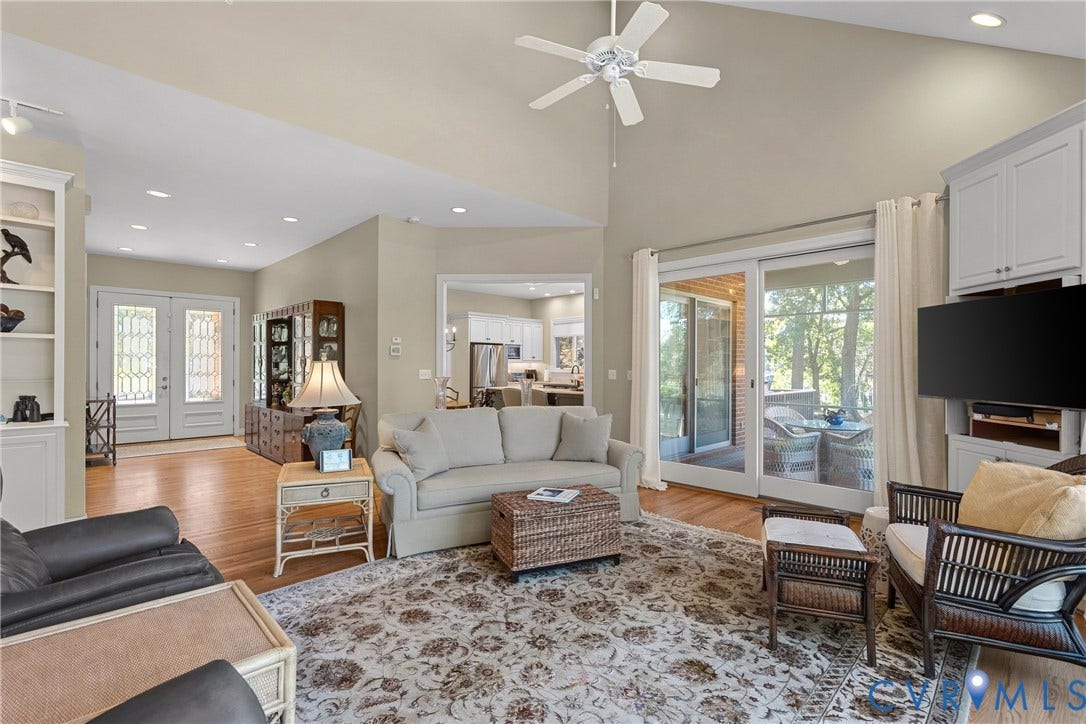 447 Tranquility Road, Reedville, VA 22539 Vaulted ceilings, wood-finish flooring, sliding glass doors to a covered outdoor area, built-in shelving, and a ceiling fan