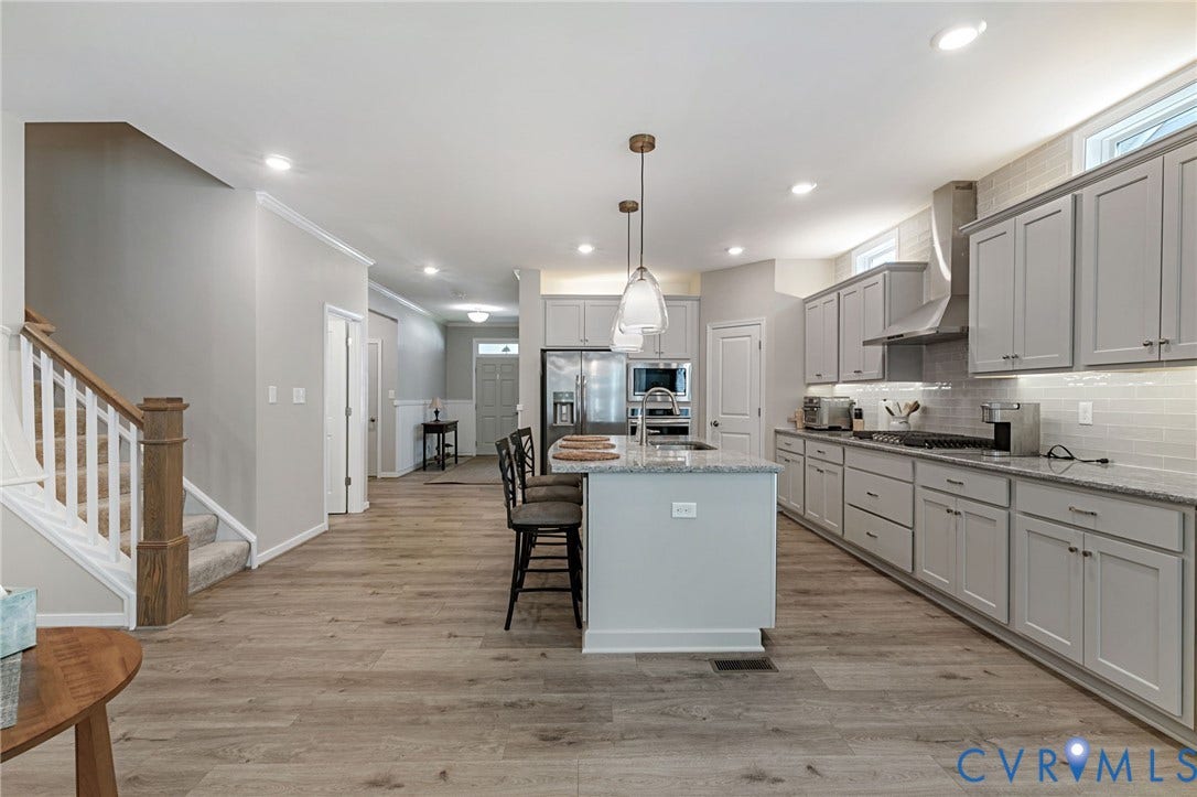 8681 Terroir Lane, Cottages At Viniterra, New Kent, VA 23124 Expansive kitchen featuring a large island with pendant lighting, stainless steel appliances, light gray cabinetry, and wood-finish flooring