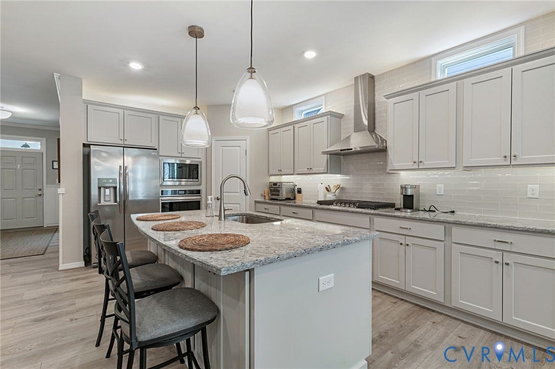 8681 Terroir Lane, Cottages At Viniterra, New Kent, VA 23124 Kitchen featuring a large central island, stainless steel appliances, light gray cabinetry, subway tile backsplash, and LVP flooring