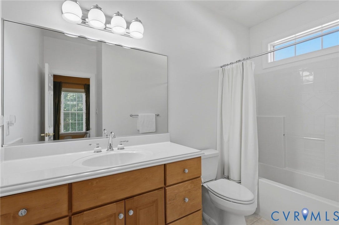 3012 Hedgeway Place, Tarrington, Midlothian, VA 23113 Elongated vanity mirror, four-light fixture, wood-finish cabinetry, integrated sink, and white shower-tub combination