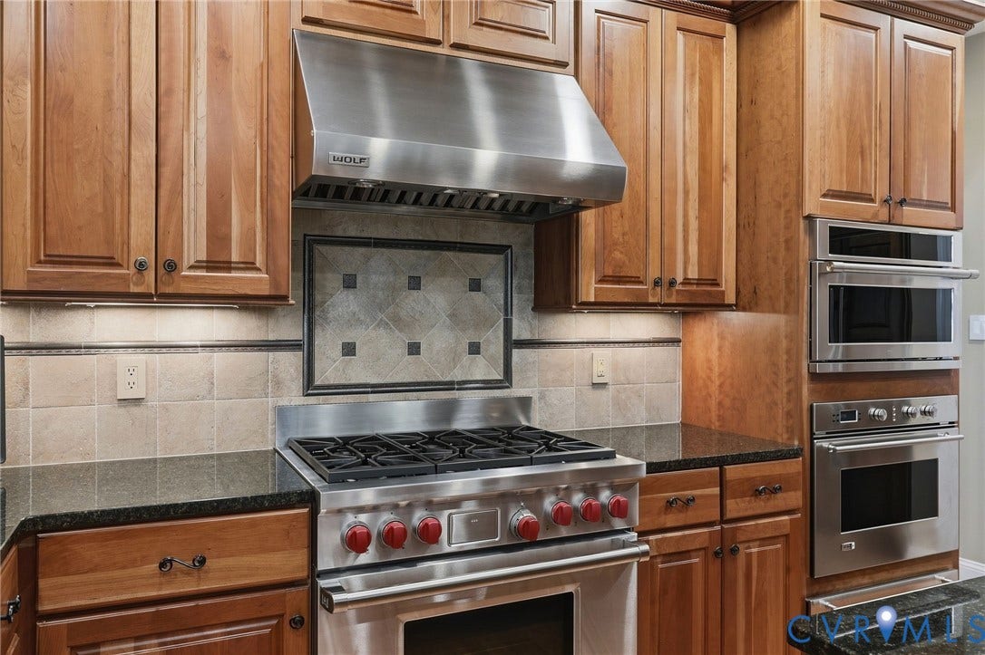 3012 Hedgeway Place, Tarrington, Midlothian, VA 23113 Stainless steel range with a professional-grade hood, built-in wall oven and microwave, stone countertops, and wood cabinetry with under-cabinet lighting