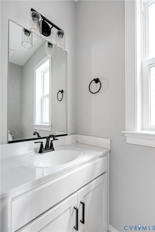White vanity cabinetry with matte black hardware, an integrated white sink, and a white countertop