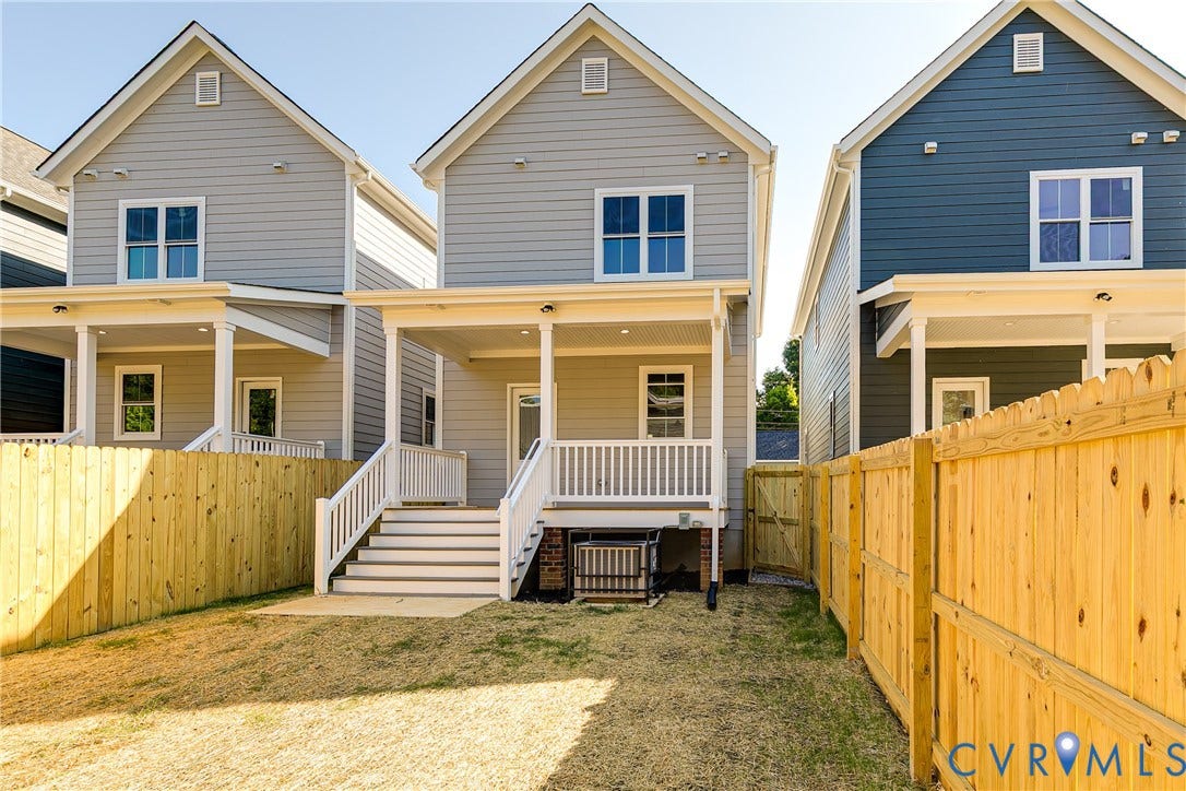 Rear elevation with light gray horizontal siding, an elevated covered porch, and white railings and stairs