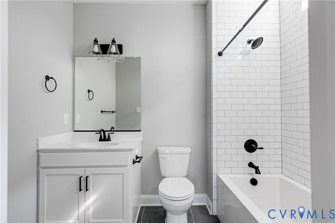 White vanity with matte black hardware, white countertop, and subway tile shower surround