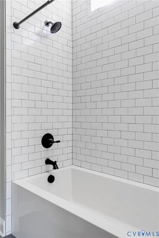 White subway tile shower surround with matte black fixtures and a white bathtub