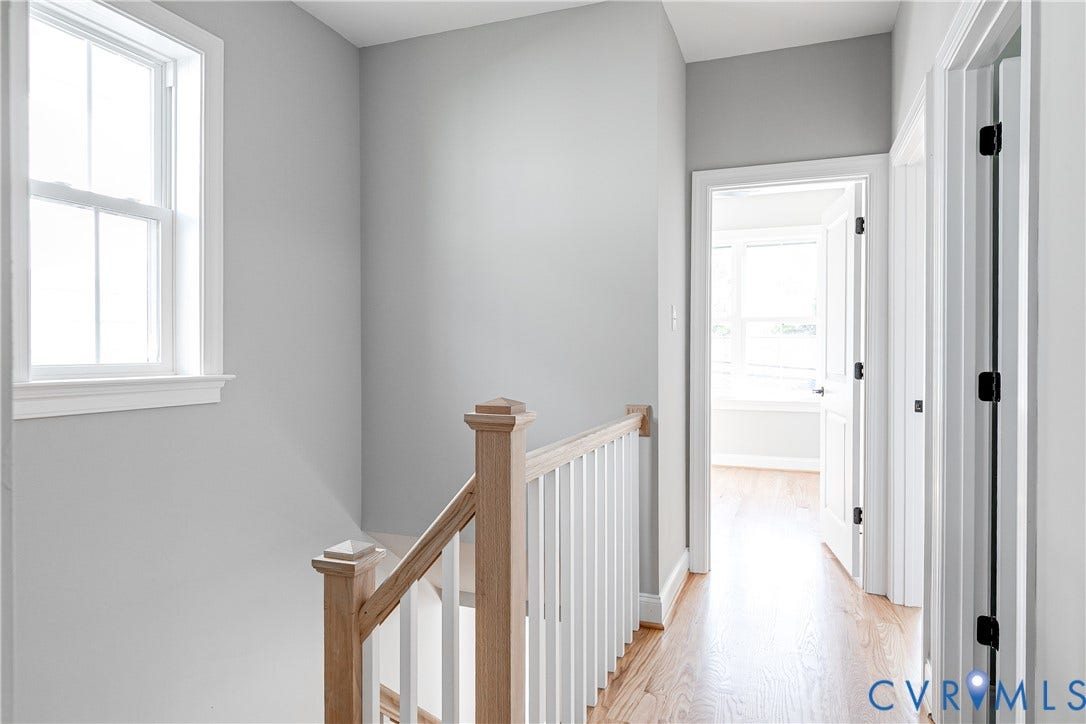 Hardwood flooring throughout, white trim, and a wood newel post with white balusters