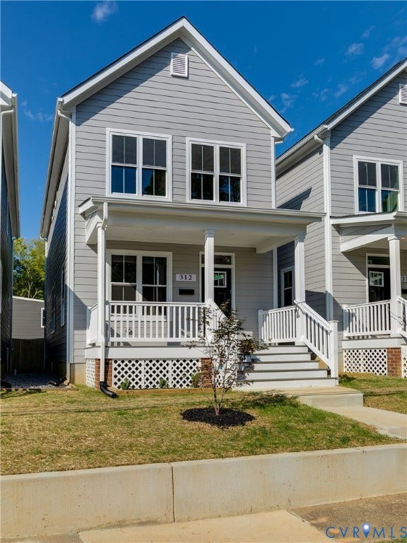 Two-story residence featuring light gray siding, white trim, a covered front porch, and a concrete walkway