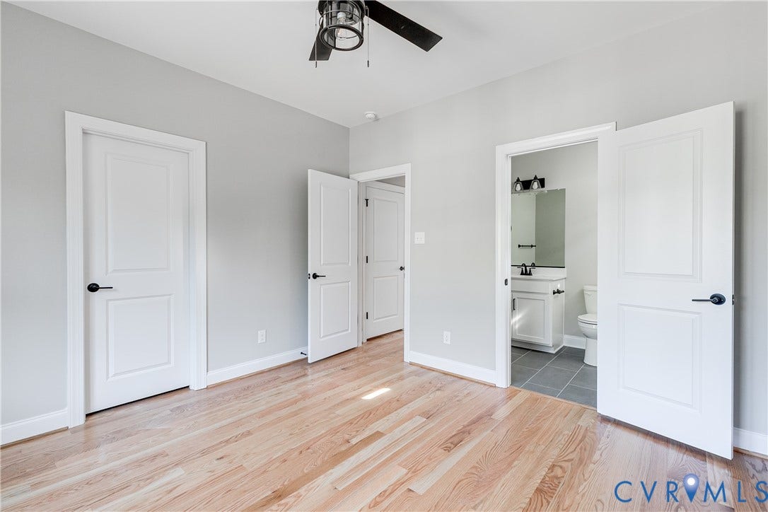 Hardwood-finish flooring, light gray wall finishes, white trim, white paneled doors, and a ceiling-mounted fan with integrated lighting