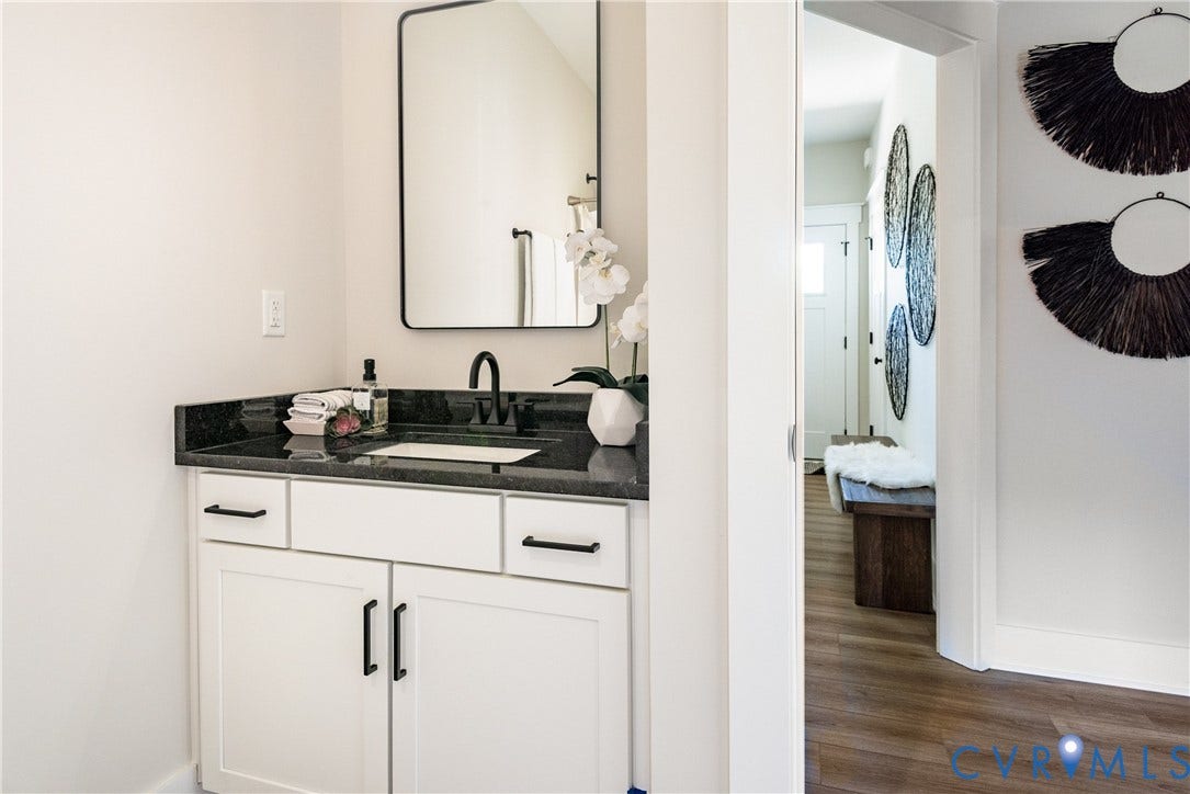 1343 Stokes Station Road, Goochland, VA 23063 White vanity cabinetry with black hardware, dark stone countertop, matte black faucet, and rectangular framed mirror