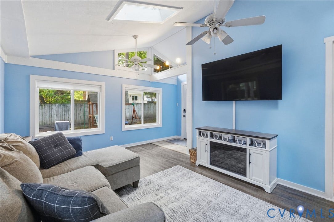 10407 Silverbrook Drive, Henrico, VA 23233 Vaulted ceiling with skylight, wood-finish flooring, multiple windows, and a built-in media console with an electric fireplace