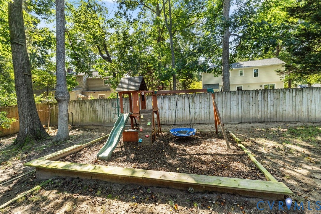10407 Silverbrook Drive, Henrico, VA 23233 Wood-fenced backyard with mature trees and a dedicated play area featuring a slide and swing set