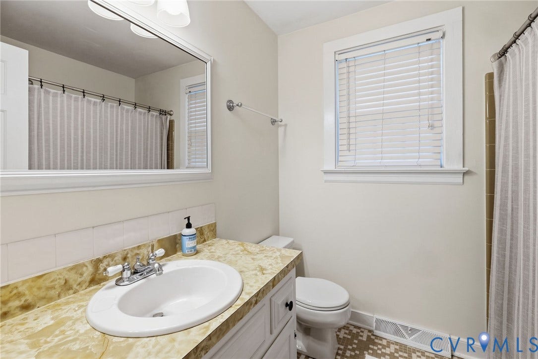 10407 Silverbrook Drive, Henrico, VA 23233 Warm-toned vanity with integrated sink, chrome fixtures, and a large framed mirror