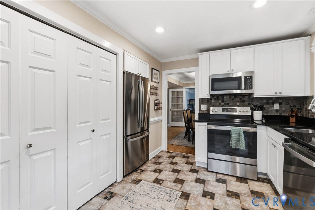 10407 Silverbrook Drive, Henrico, VA 23233 White cabinetry, stainless steel appliances, black countertops, tile backsplash, and patterned floor tile