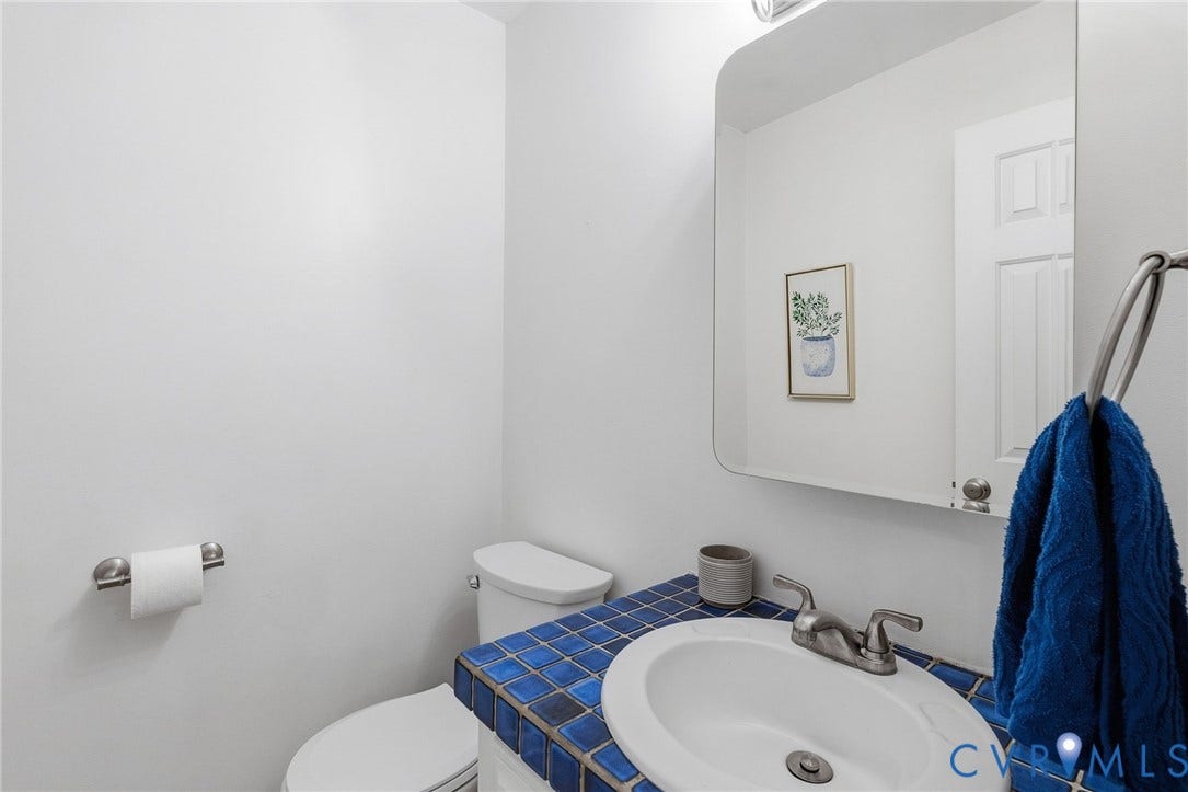10407 Silverbrook Drive, Henrico, VA 23233 White walls with a wall-mounted paper holder, toilet, and a sink with a blue tiled countertop