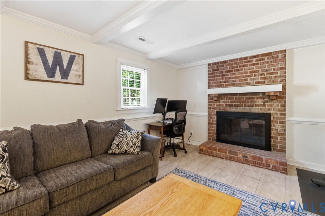 10407 Silverbrook Drive, Henrico, VA 23233 Exposed brick fireplace with a white mantel, tiled hearth, and a window with white blinds