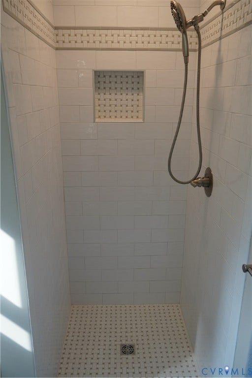 10227 Acworth Drive, Glen Allen, VA 23060 Tiled shower featuring subway tile walls, a decorative tile accent band, and a recessed niche. and basketweave tile floor