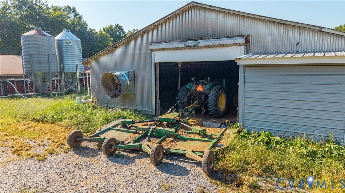 78 Bowling Lane, Cumberland, VA 23040 Corrugated metal barn with a roll-up door, exterior fan, and two large metal silos