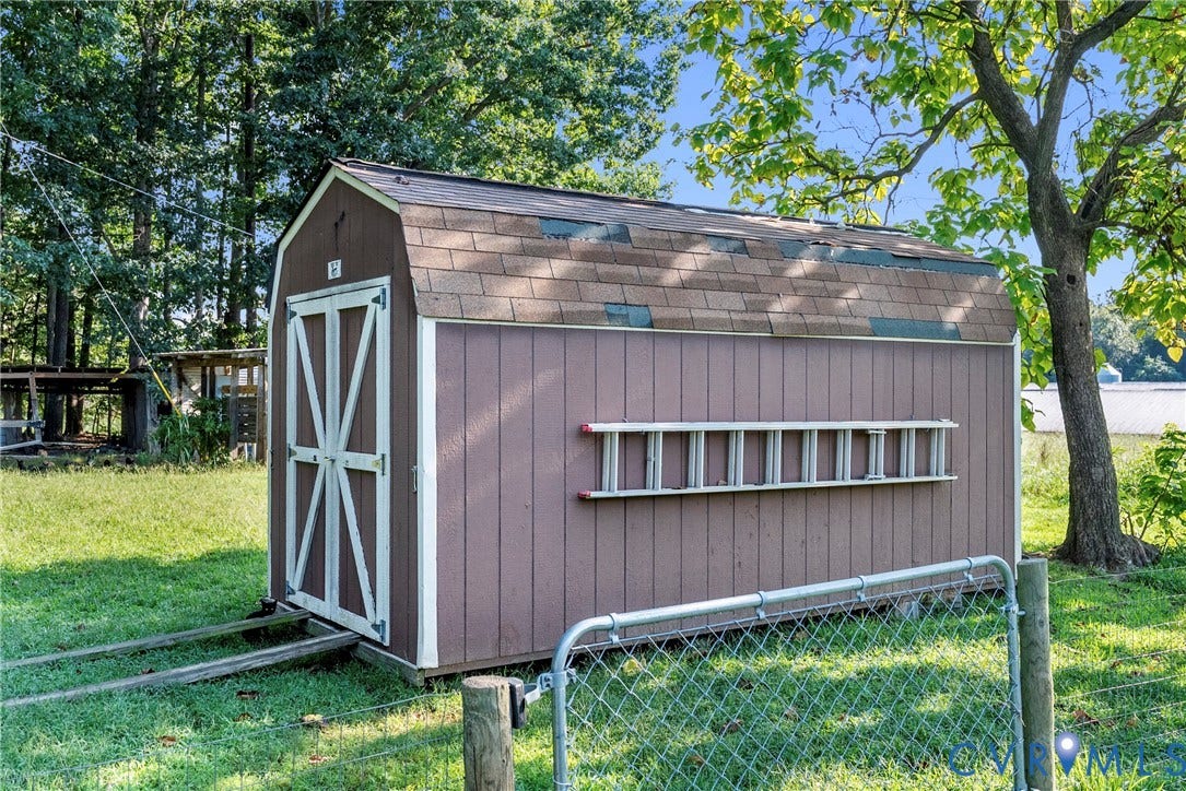 78 Bowling Lane, Cumberland, VA 23040 Gable roof storage shed with double doors, wood-finish siding, and a chain-link gate