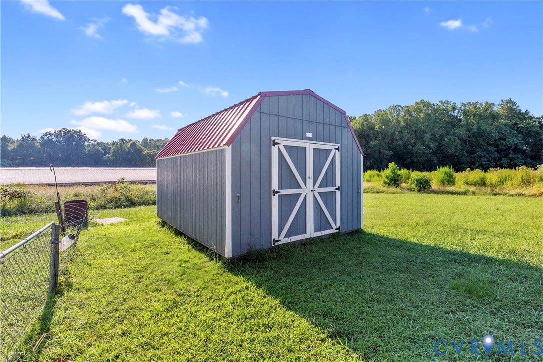 78 Bowling Lane, Cumberland, VA 23040 Detached storage building with a red metal roof, blue siding, and white double doors, set on a manicured lawn