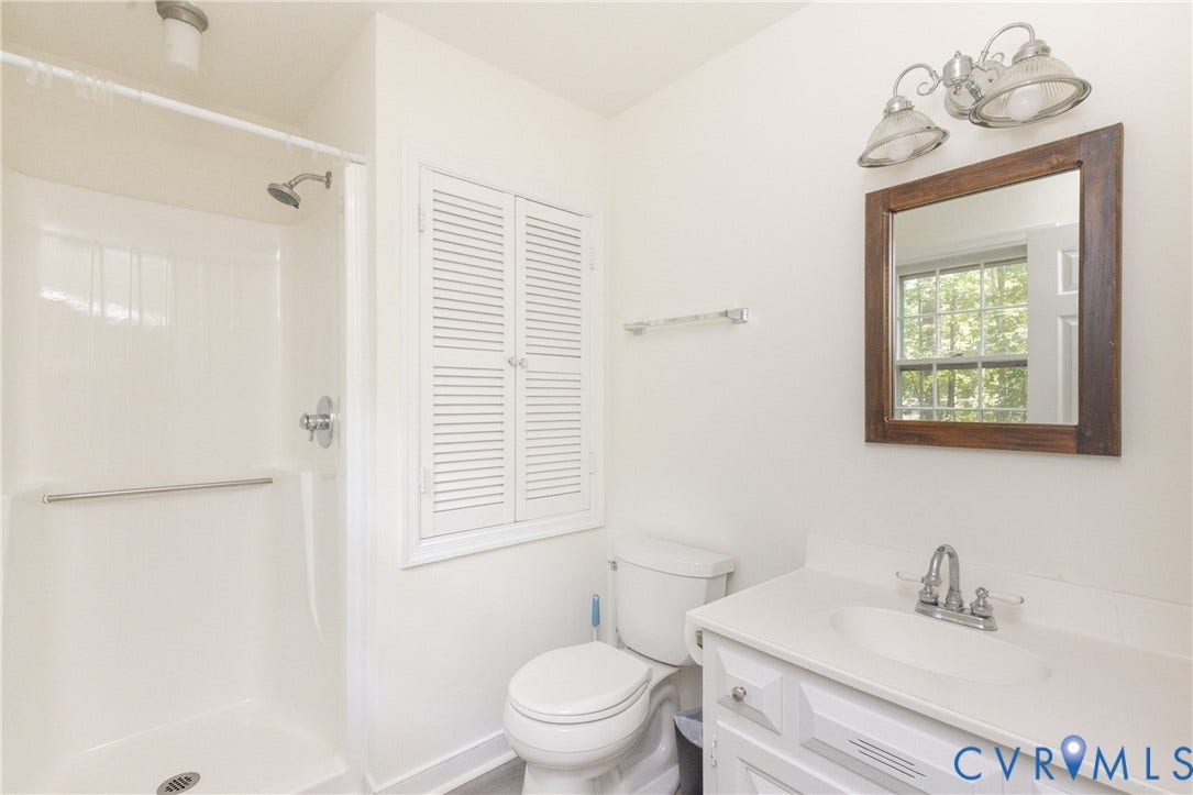 2765 Briarpatch Lane, Powhatan, VA 23139 White vanity with a single basin sink, chrome faucet, and wood-framed mirror