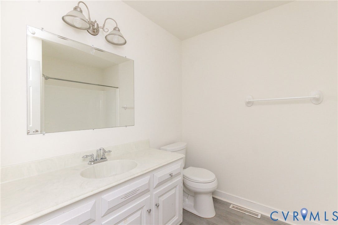 2765 Briarpatch Lane, Powhatan, VA 23139 White vanity with an integrated sink, polished chrome faucet, and rectangular mirror with a brushed nickel light fixture