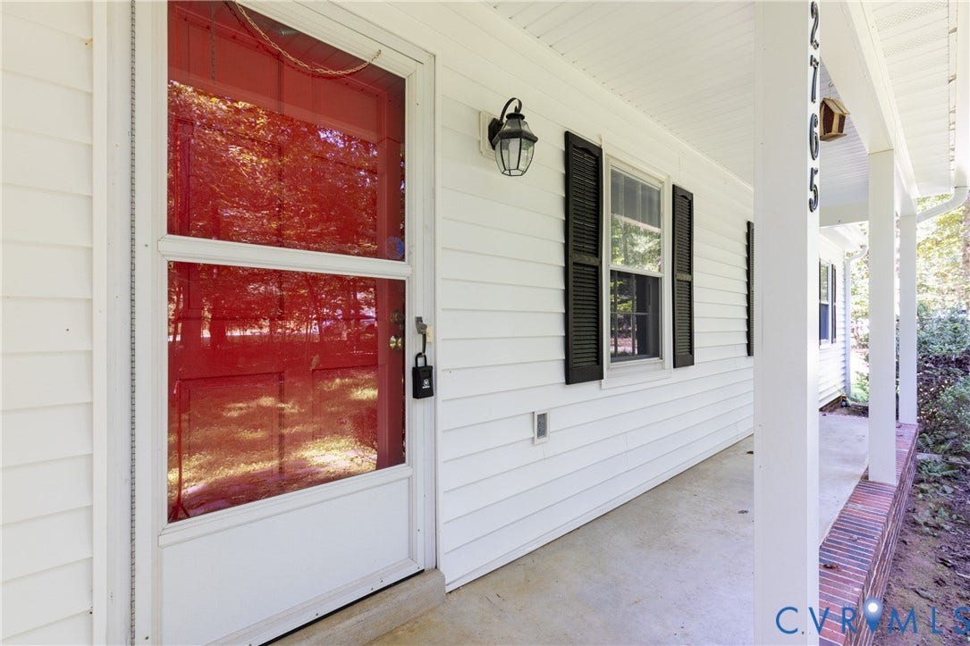 2765 Briarpatch Lane, Powhatan, VA 23139 White siding exterior with a red entry door, black louvered shutters, and a covered porch with white columns