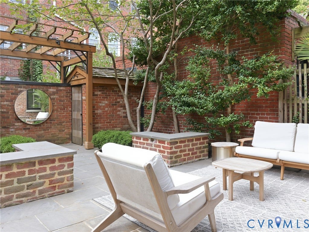 Private brick patio featuring stone pavers, built-in brick planters with stone caps, and a wooden pergola