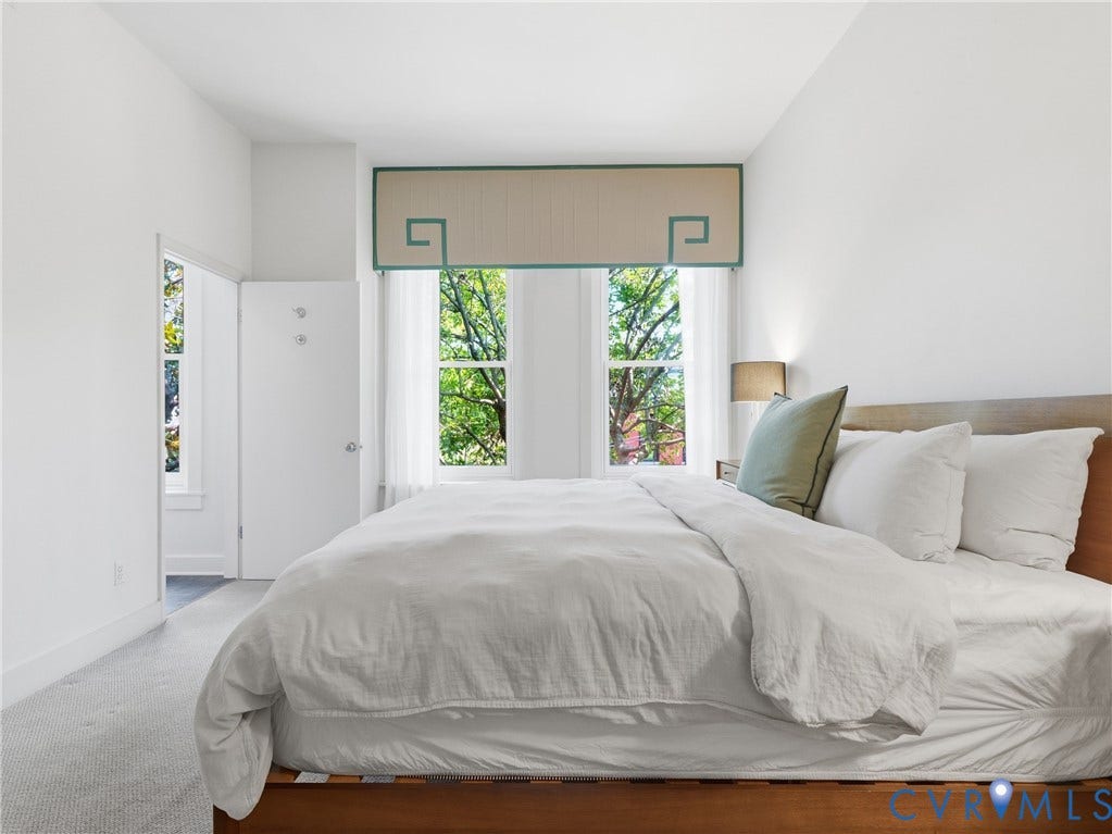White walls with light-toned carpet, two windows with white trim, and a decorative valance