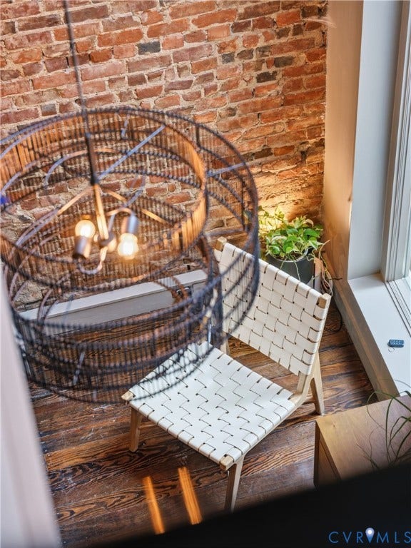 Exposed brick wall, wood-finish flooring, and a large window