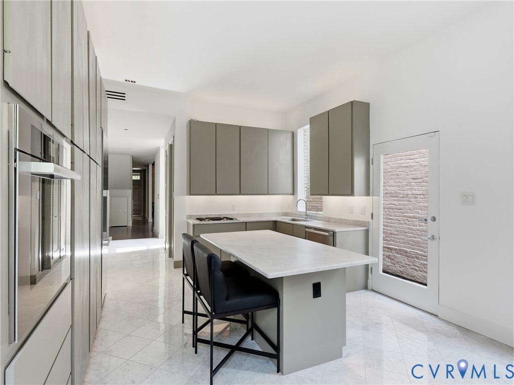 Modern kitchen with a U-shaped island, under-cabinet lighting, integrated stainless steel appliances, and tile flooring