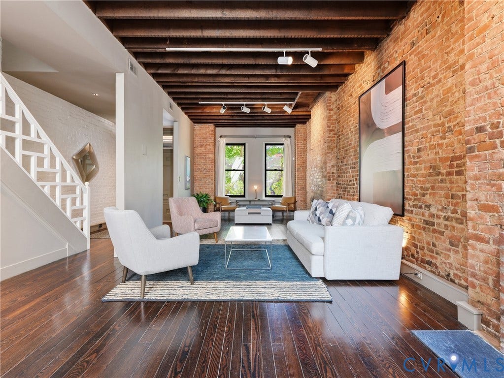 Exposed brick walls, dark wood-finish flooring, and a wood-beamed ceiling