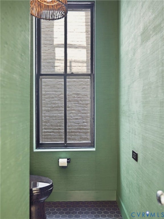 Hexagonal floor tiling, a black-framed window, and a dark toilet